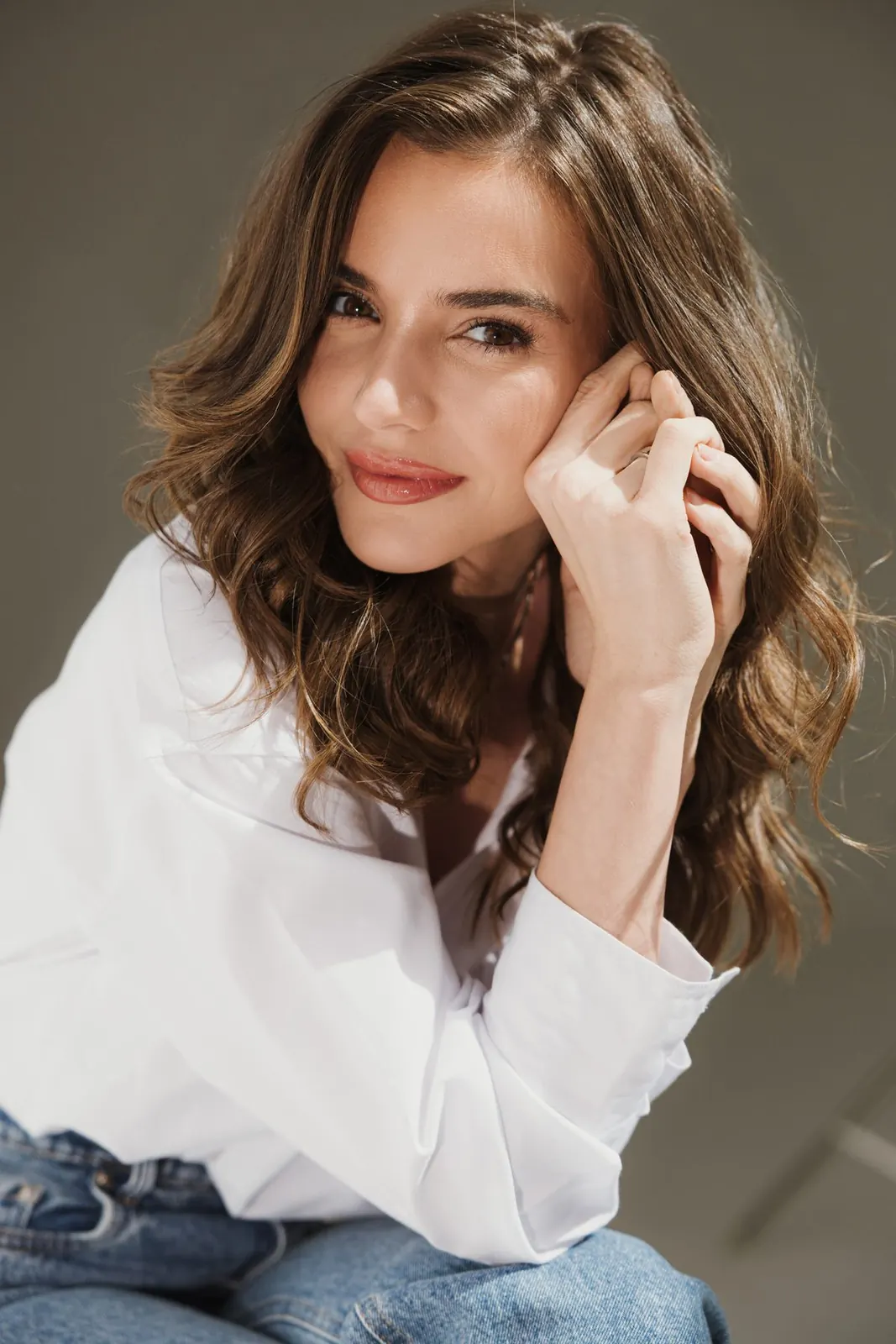 Dra. Joana Webber sorrindo, com a mão no rosto