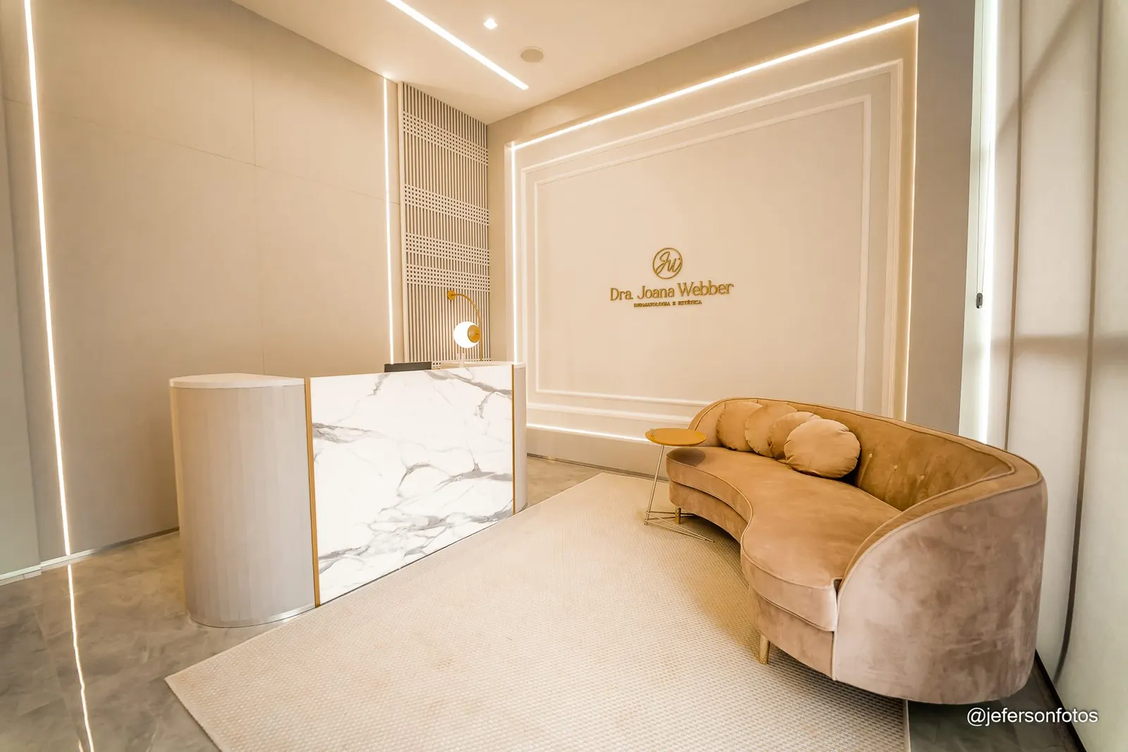 Recepção da Clínica Joana Webber com parede boiserie e logo em dourado