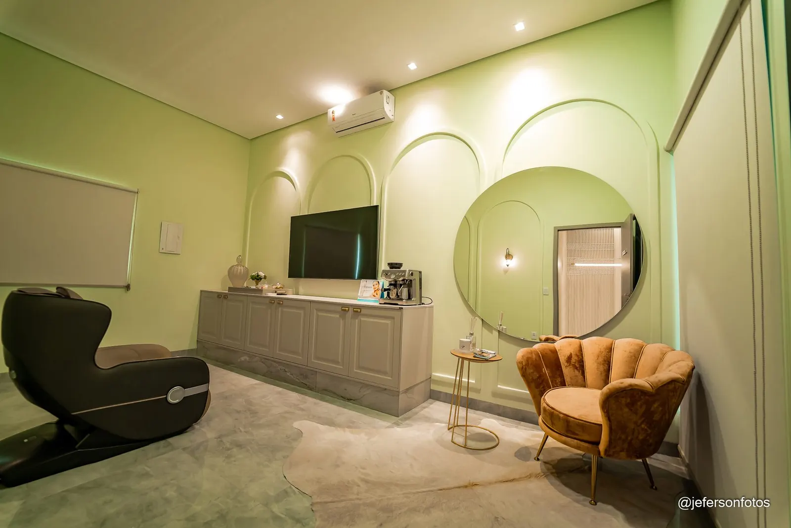 Sala em verde-sálvia com poltrona rosé e espelho redondo