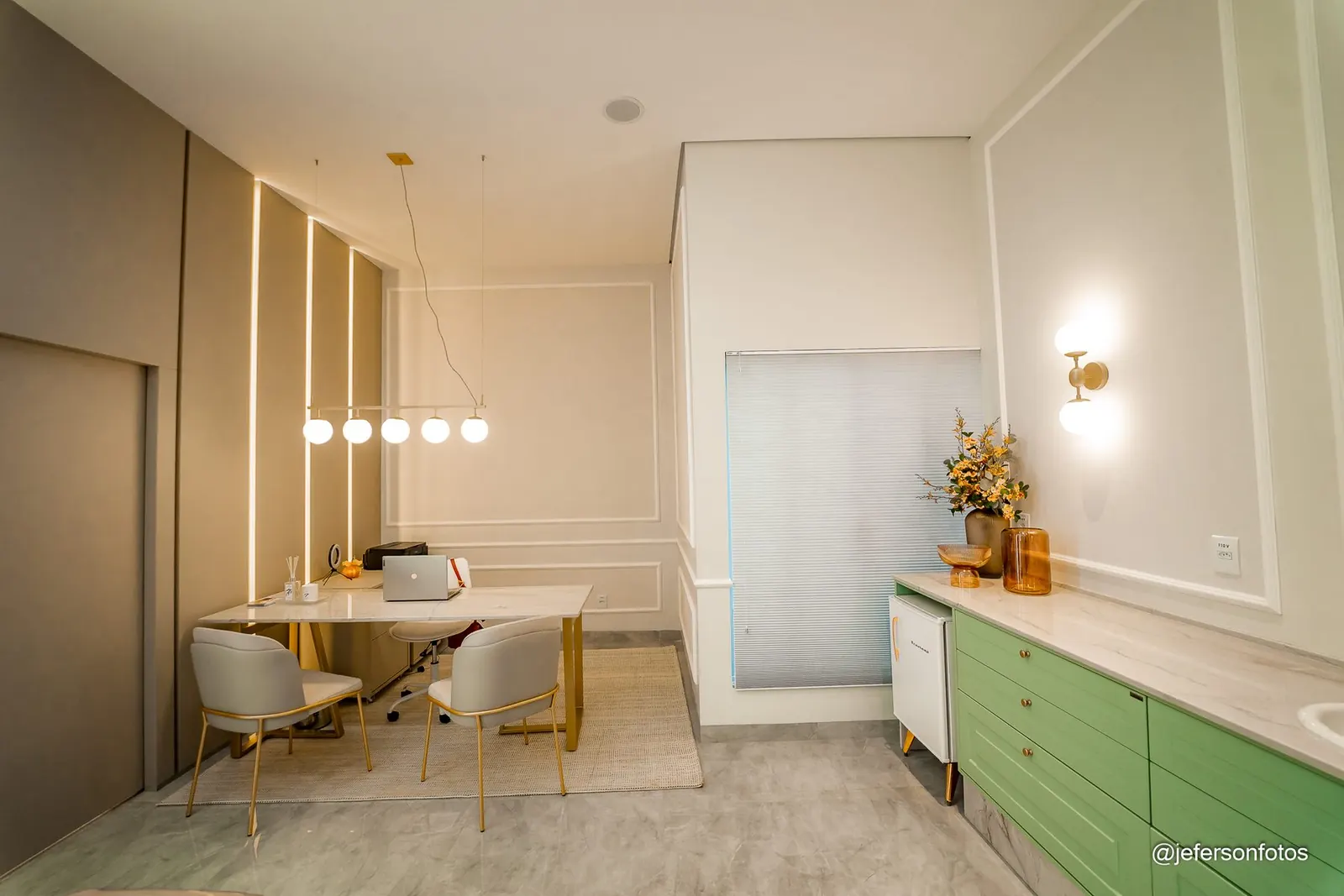 Consultório com mesa, luminária e armários em verde-sálvia